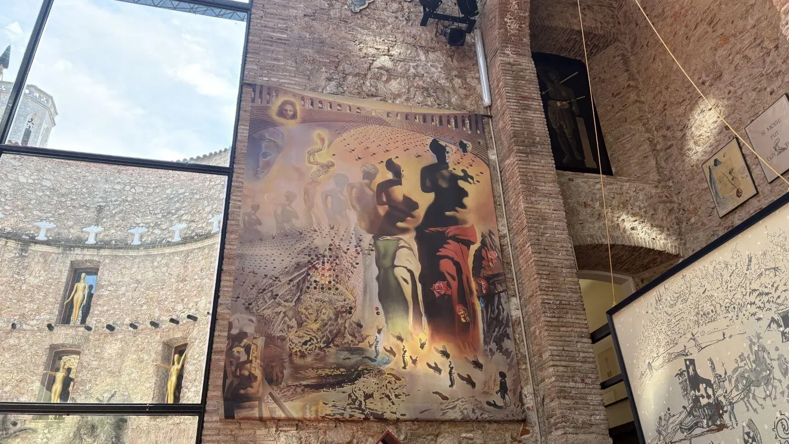 A large Salvador Dalí painting hanging on a brick wall inside the Dalí Theatre-Museum in Figueres, Spain