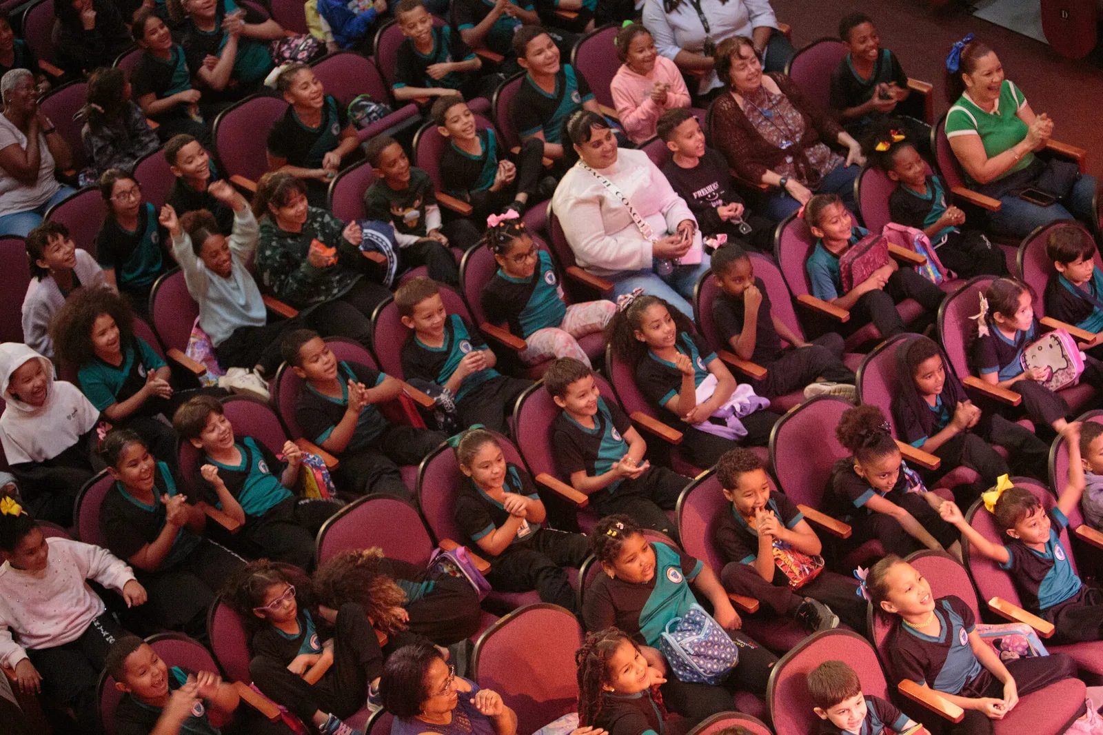Schoolchildren laughing and clapping in the seats of a theater during an Olga Iglesias Project performance