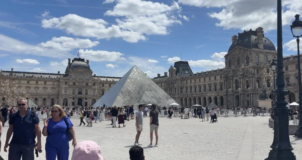 The glass pyramid in the courtyard of the Louvre in Paris under a blue summer sky